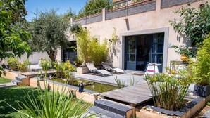A modern outdoor patio with a pool, lounge chairs, and a variety of plants. - Villa Ambrosia (Narbonne)