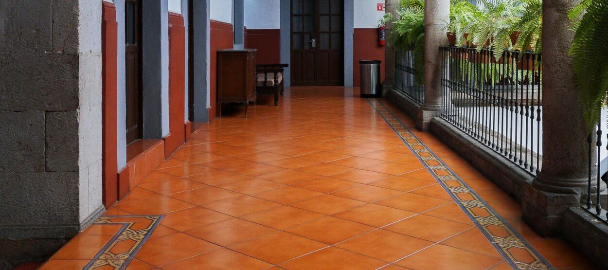 A corridor with a tiled floor, a bench, and a door at the end.