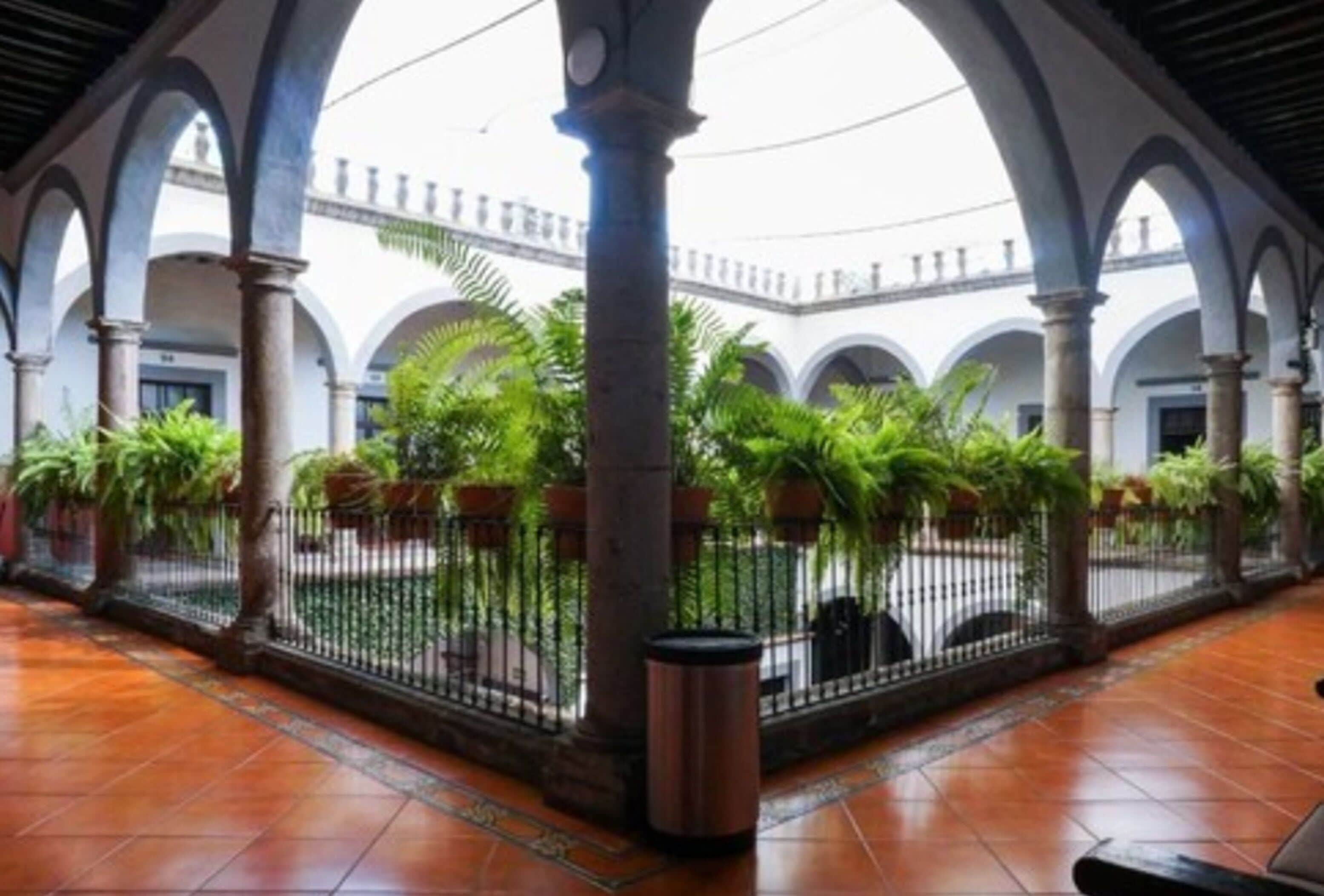 An indoor courtyard with arches, tiled flooring, and potted plants.