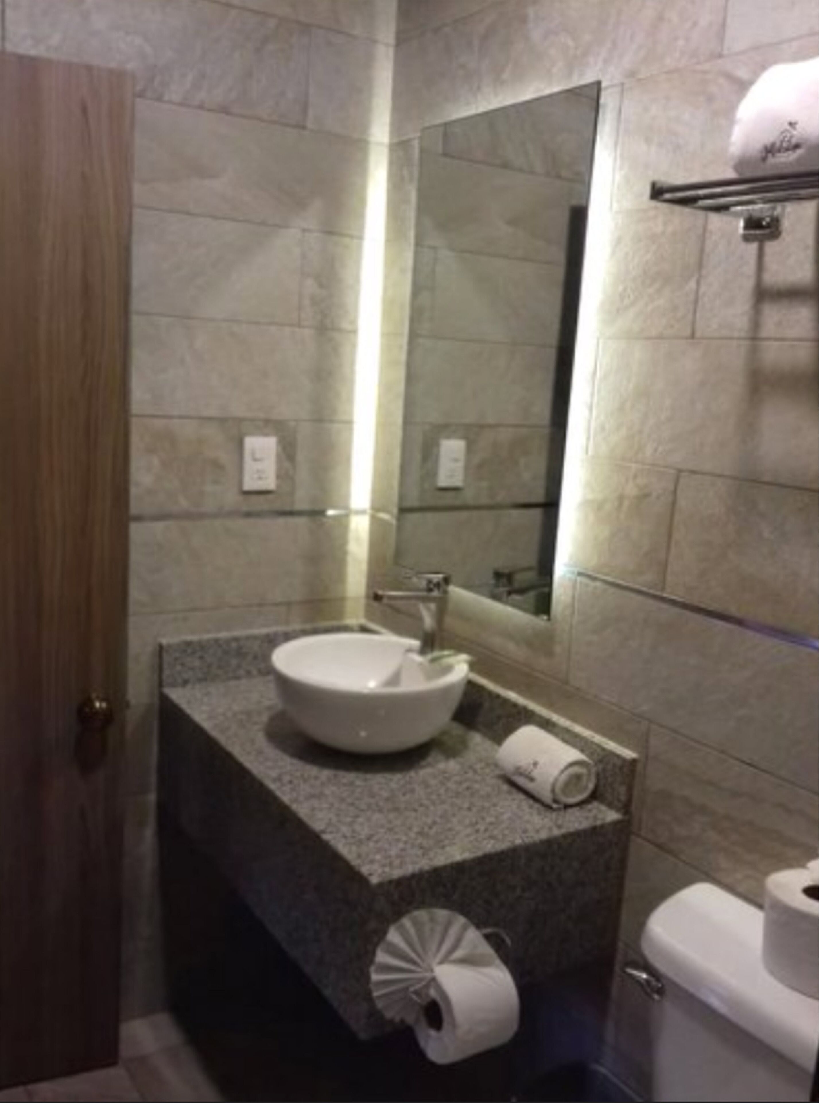 A bathroom with a white sink, a mirror, and a toilet.