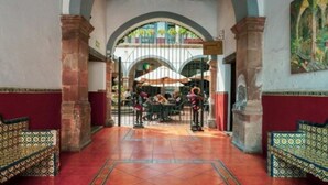 An interior courtyard with a tiled floor, a central seating area, and a gate leading to an outdoor space. - Hotel Hidalgo (Querétaro)