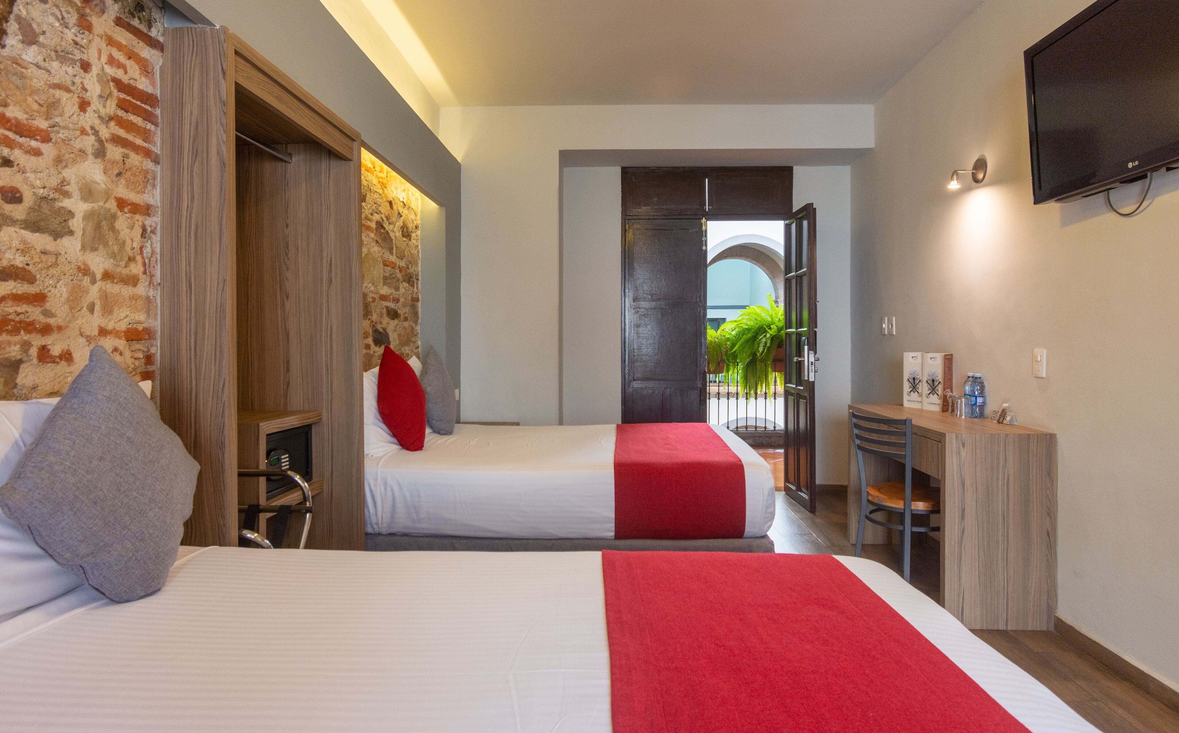 Una habitación de hotel con cama, escritorio, televisión y vistas al exterior.