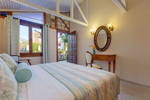 Un dormitorio con cama, escritorio, silla, espejo y vistas al exterior.