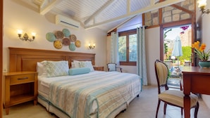 Un dormitorio con cama, mesitas de noche, una silla, un escritorio y vistas al exterior.