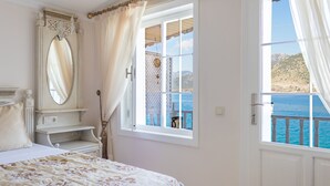 Un dormitorio con cama, cómoda, espejo y ventana con vista al mar.