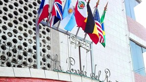 Une entrée d’immeuble ornée de plusieurs drapeaux nationaux et d’une enseigne indiquant « La Posada del Rey ».