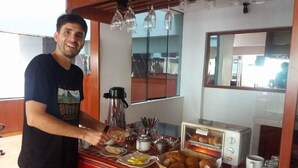 Une personne servant des plats à un buffet, où l'on trouve différents mets, une machine à café et un grille-pain.