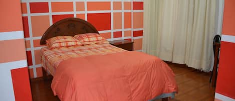 A bedroom with a wooden bed, a nightstand, and a window with curtains.