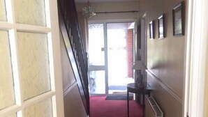 A narrow hallway with a red carpet, a door on the left, and a radiator on the right. - Clooniff House (Galway)
