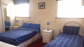 A bedroom with two beds, a dresser, and a mirror. - Clooniff House (Galway)