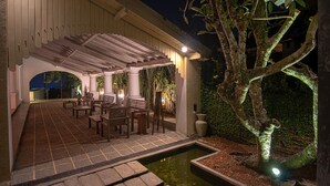 An outdoor covered seating area with wooden benches and a small water feature. - The Lady Hill Hotel (Galle)