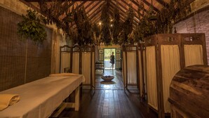 A traditional spa room with wooden floors, a central seating area, and a person standing in the doorway. - The Lady Hill Hotel (Galle)