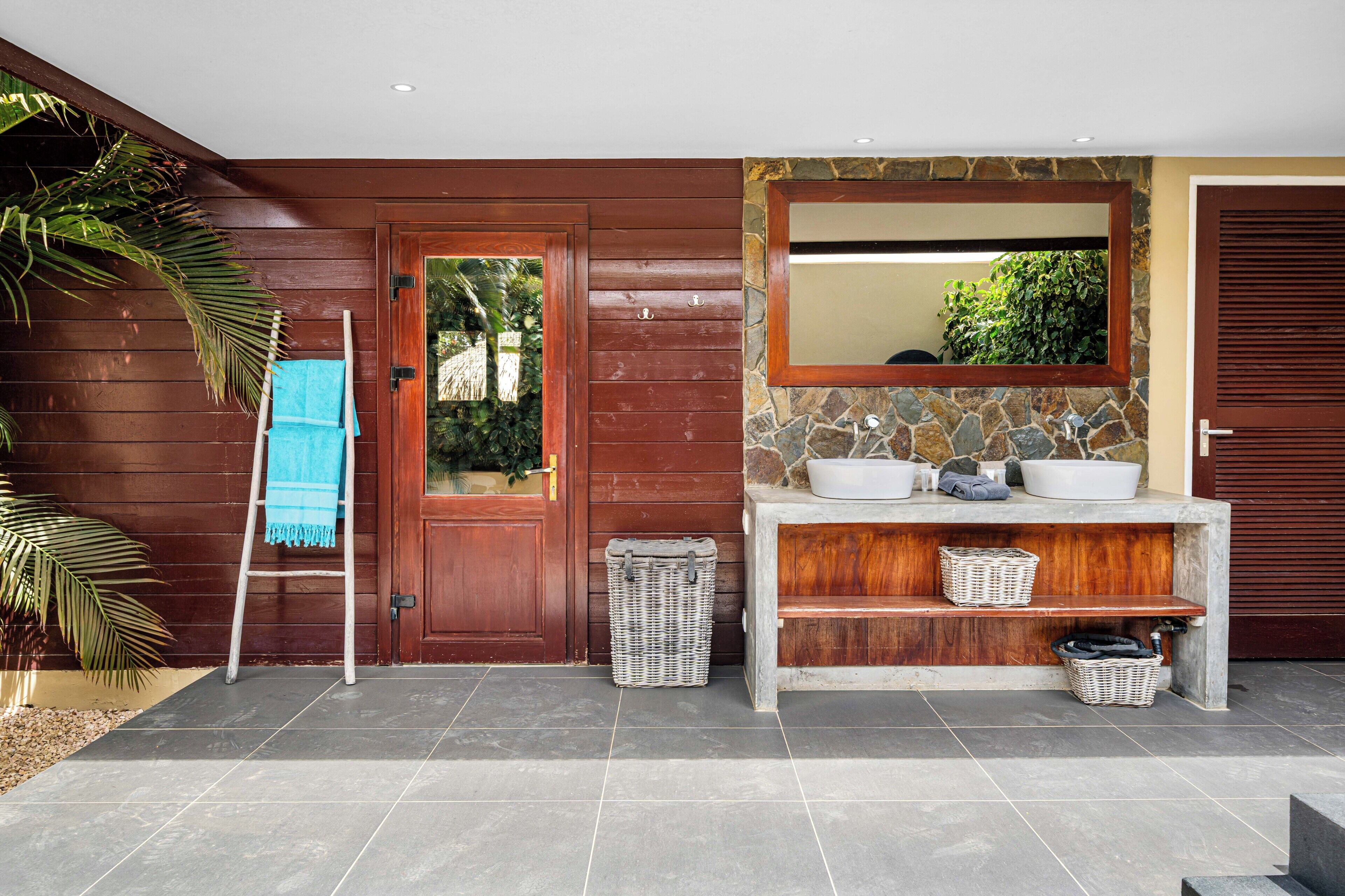 A bathroom with a wooden door, a stone wall, a mirror, and a sink.