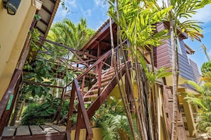 A wooden staircase leading to a building with a yellow exterior, surrounded by lush tropical vegetation. - Bamboo Bonaire by Boutique Bonaire Unique Resorts (Kralendijk)