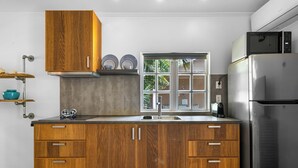 Cozinha moderna com armários de madeira, geladeira de aço inoxidável e janela com vista para o verde.