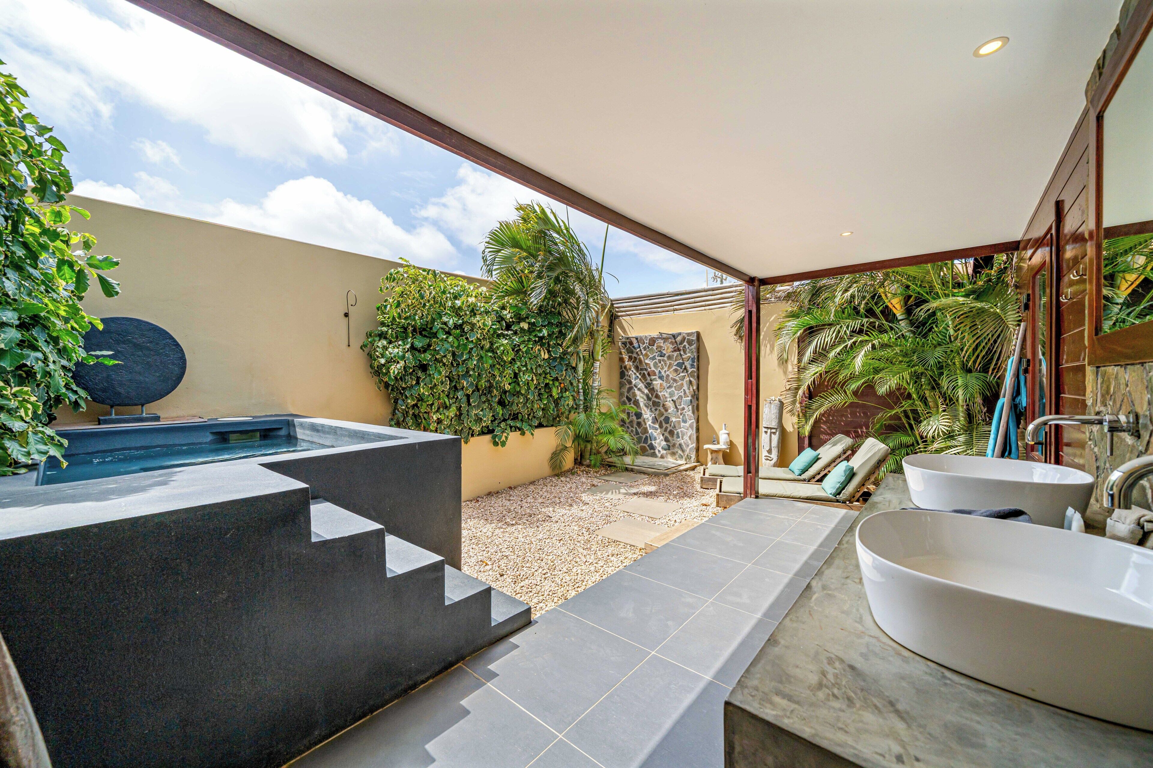 A modern bathroom with a large bathtub, a separate sink, and a hot tub.