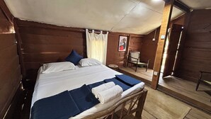 A wooden room with a bed, a chair, and a small table.