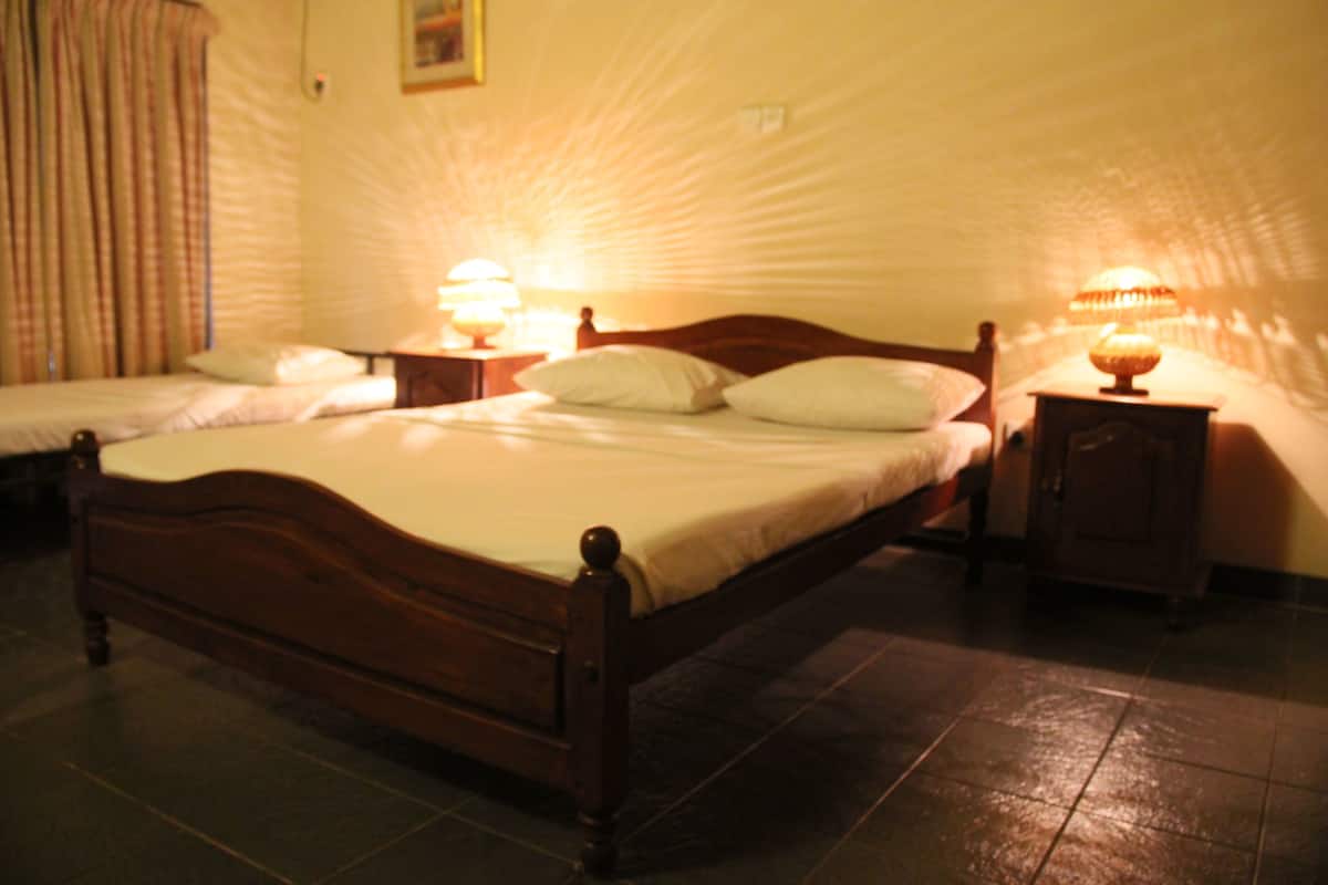 A room with a large bed, two bedside tables with lamps, and a wooden headboard.