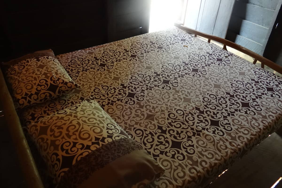 A bed with patterned bedding and a wooden headboard.