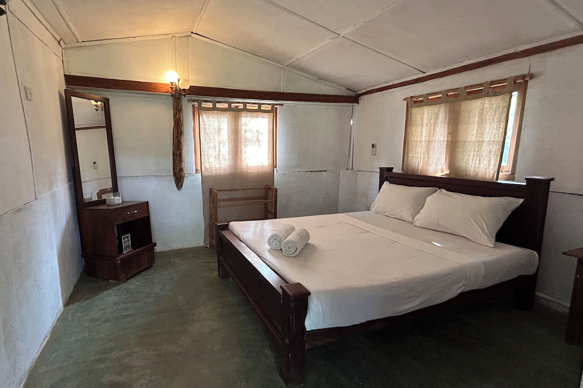 A bedroom with a wooden bed, a nightstand, a mirror, and a window with curtains.