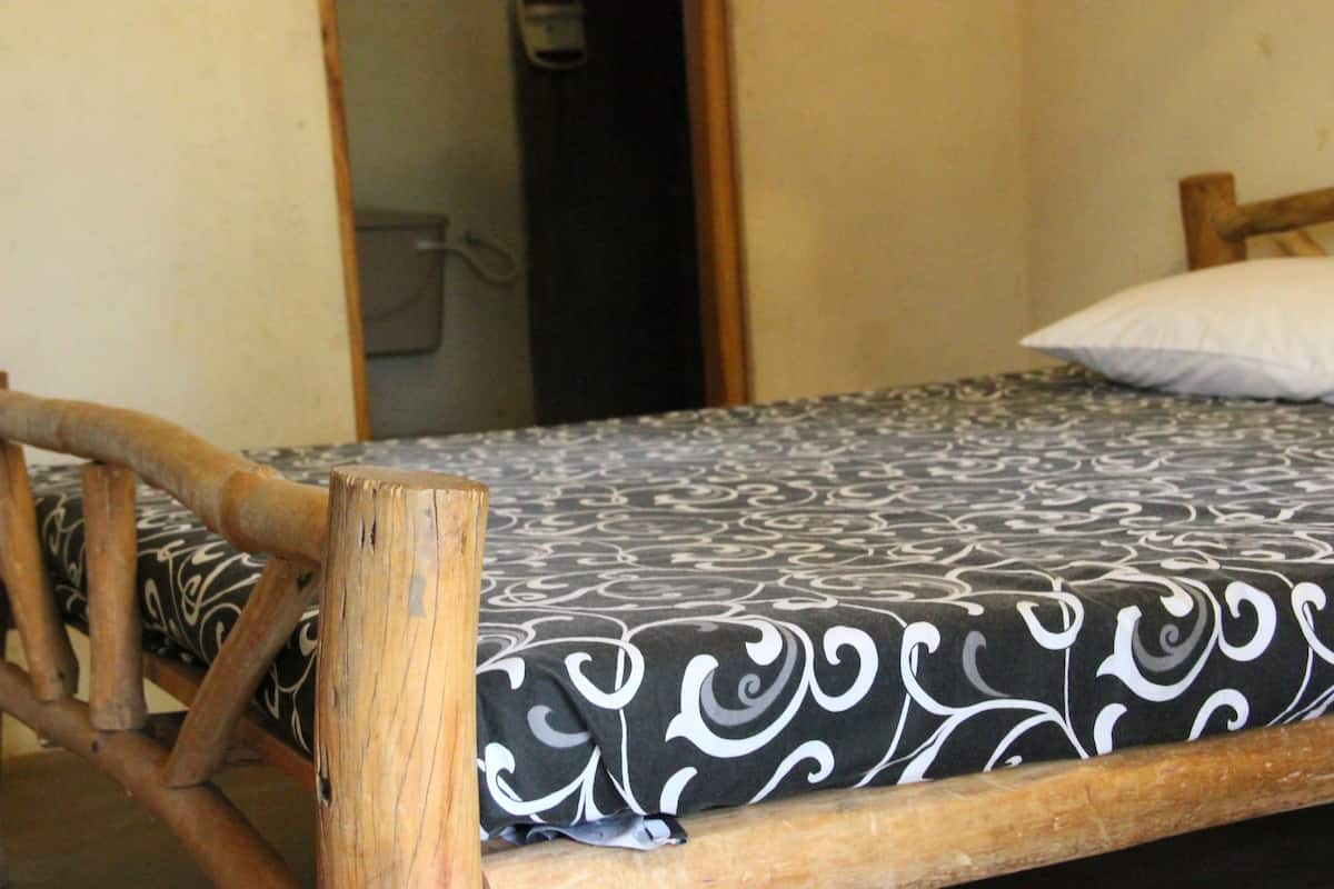 A bed with a patterned bedspread and a wooden headboard.