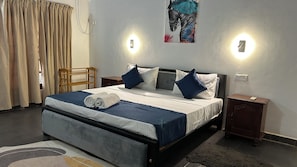 A hotel room with a large bed, two bedside tables, a headboard, and a painting on the wall.
