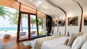 A modern bedroom with a large bed, a view of the beach, and a wooden deck. - Iniala Beach House (Takua Thung)