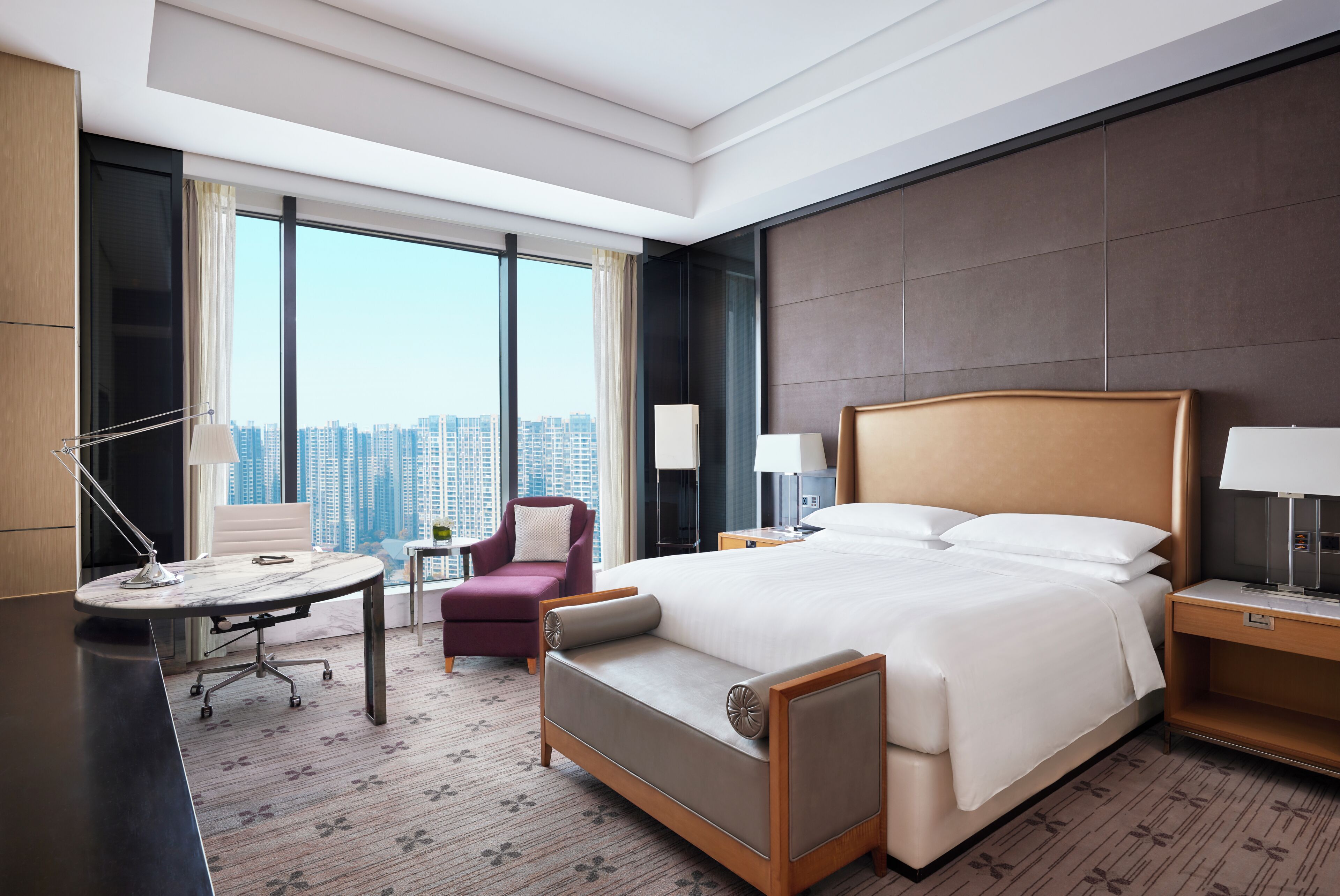 Una habitación de hotel con una cama grande, un escritorio, una silla y vistas a la ciudad.