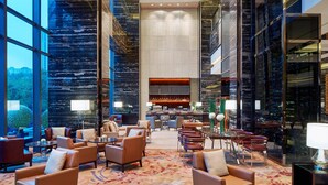 Eine geräumige Lobby mit Ledersitzgelegenheiten, einem Barbereich und großen Fenstern mit Blick auf die Stadtlandschaft.