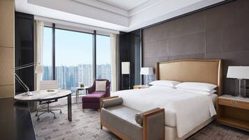 Ein Hotelzimmer mit einem großen Bett, einem Schreibtisch, einem Stuhl und Blick auf die Stadt.