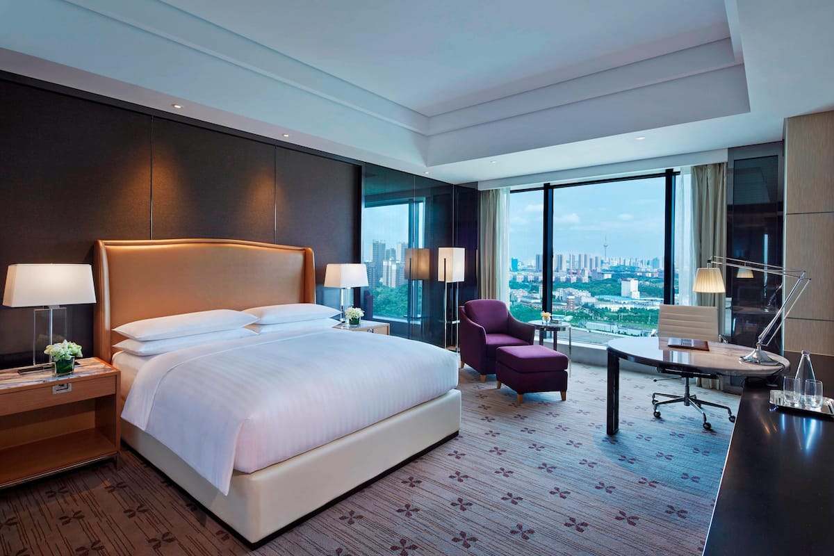 Habitación de hotel moderna con una cama grande, un escritorio, una silla y vistas a la ciudad.