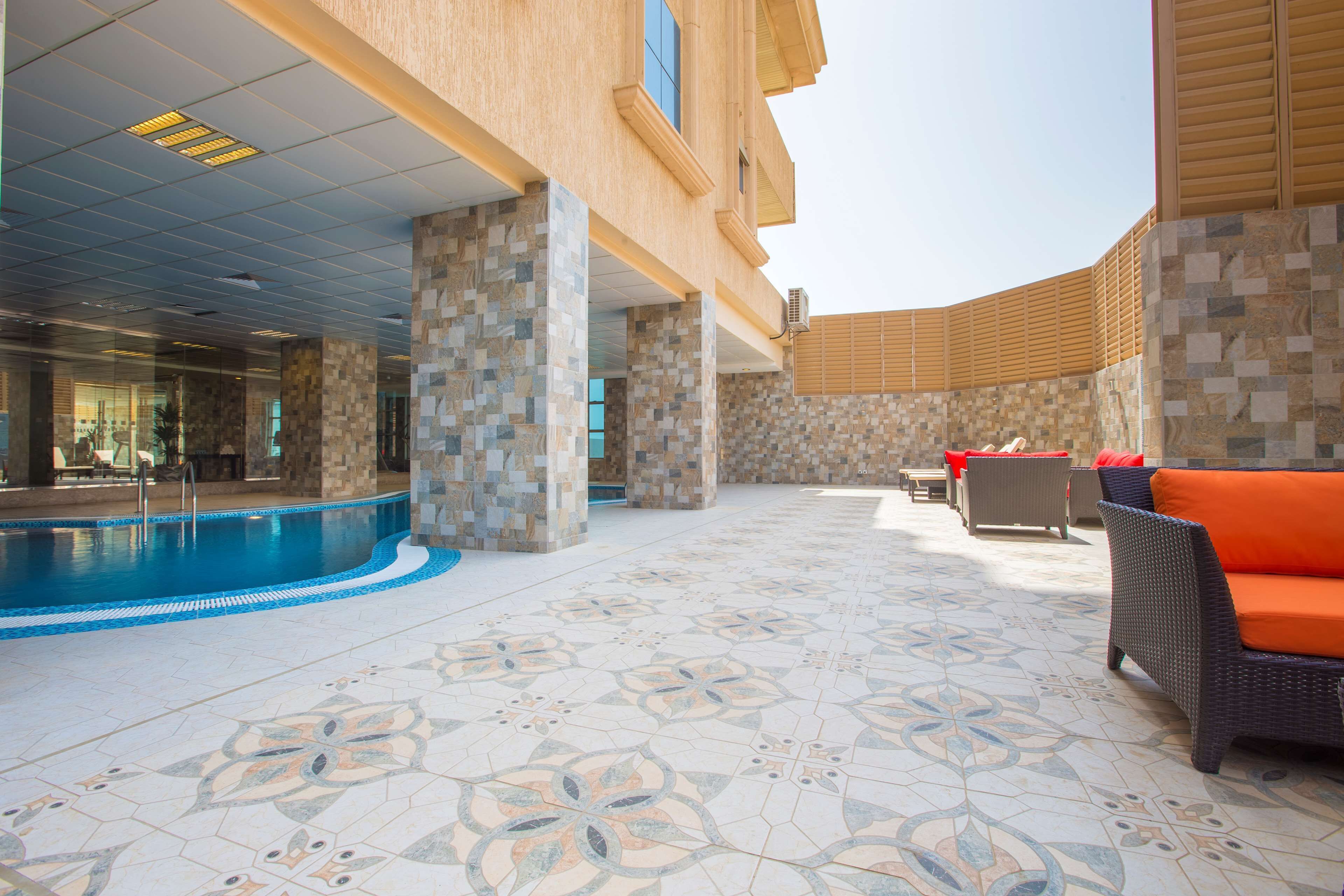 A pool area with a tiled floor, a lounge with a sofa, and a covered seating area.