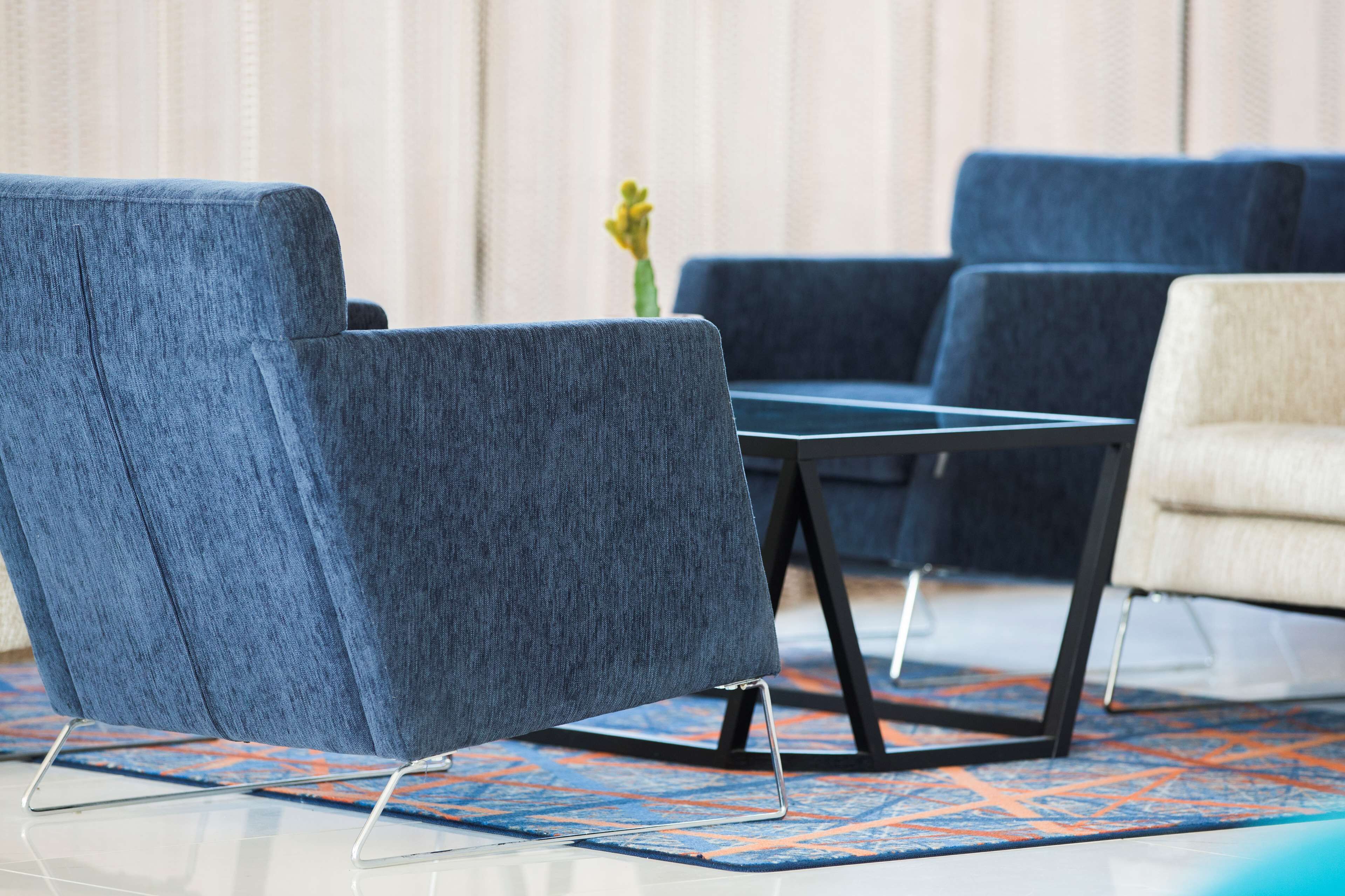 A modern living room with a blue sofa, a white armchair, and a small table.