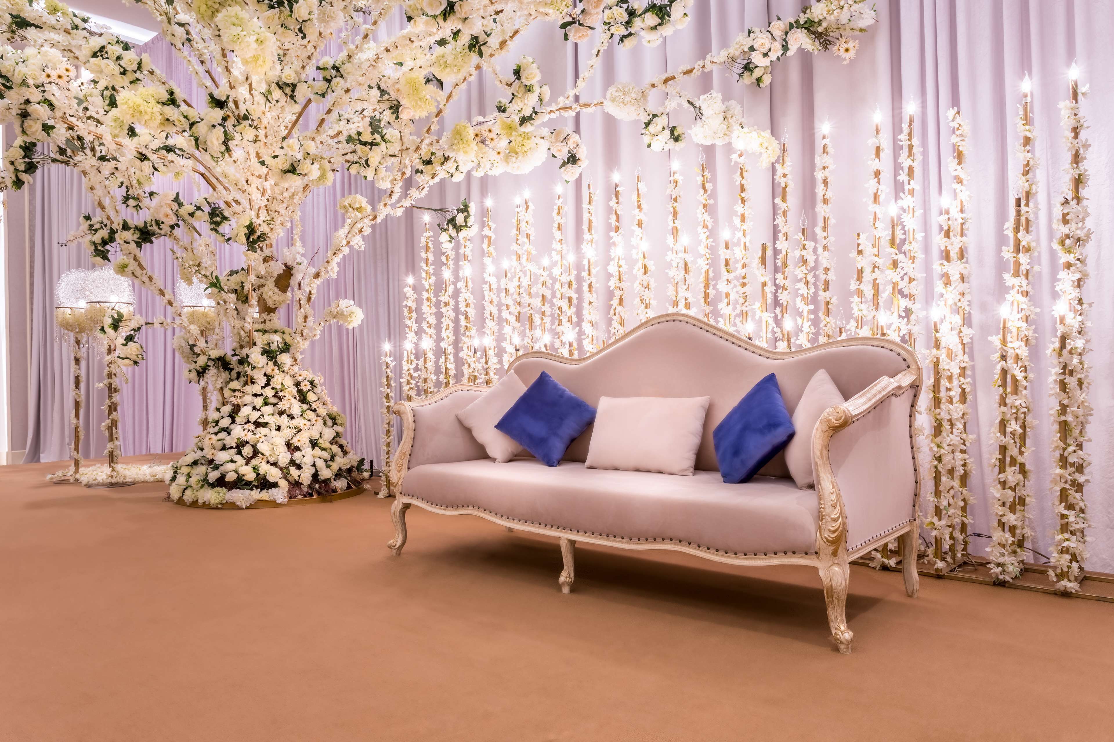 A luxurious room with a plush sofa, elegant drapery, and a floral centerpiece.