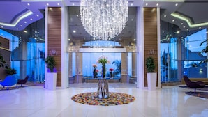 A modern lobby with a large chandelier, a reception desk, and a colorful rug. - Radisson Blu Hotel, Jeddah Plaza (Jeddah)