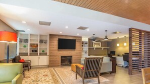 Una sala de estar moderna con chimenea, zona de estar y televisor montado en la pared.