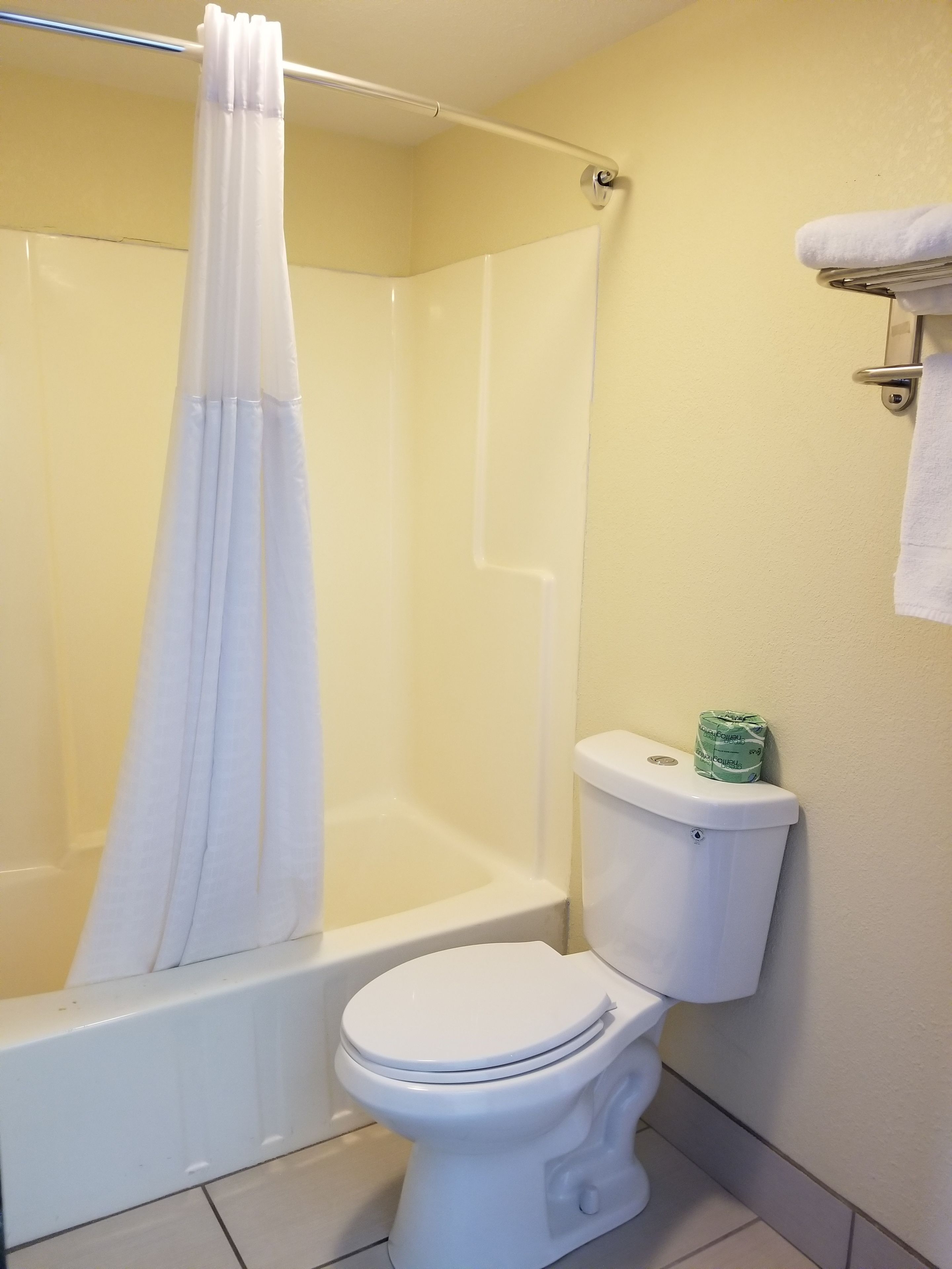 Un baño con ducha, inodoro y toallero.