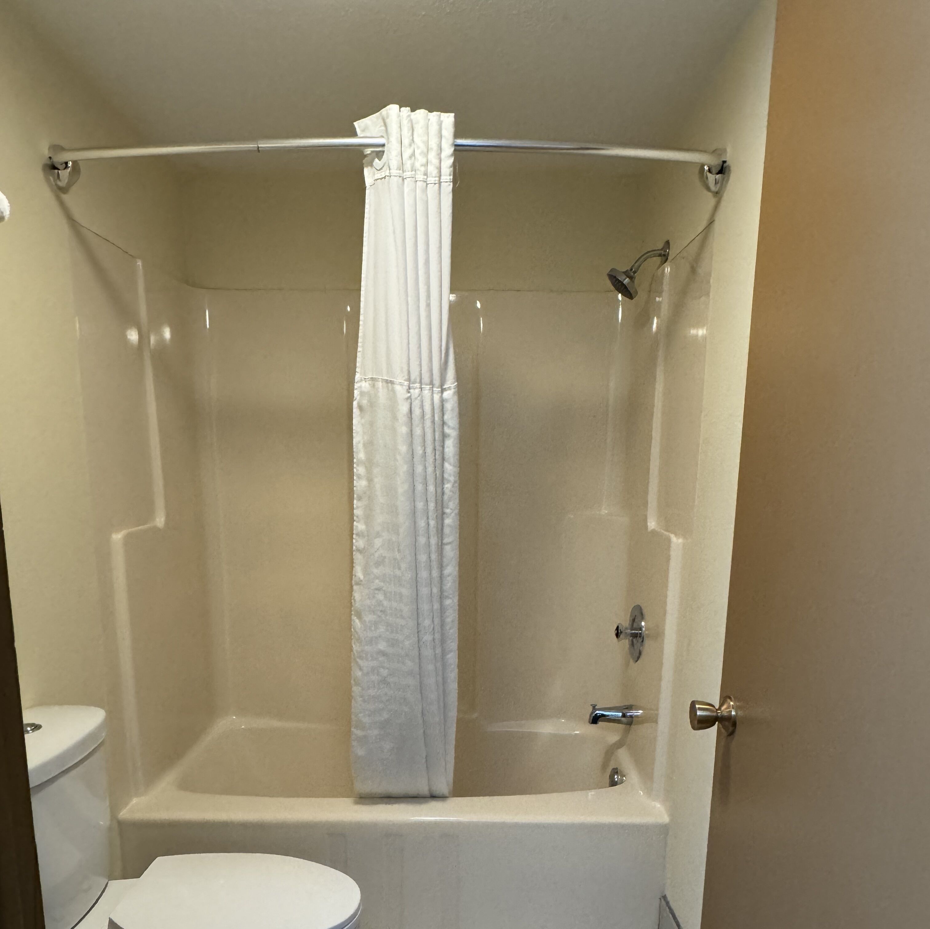 A bathroom with a bathtub, toilet, and shower curtain.
