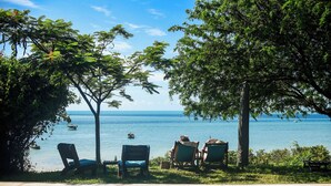 A poolside area with lounge chairs and a view of the sea. - Casa Babi (Vilanculos)