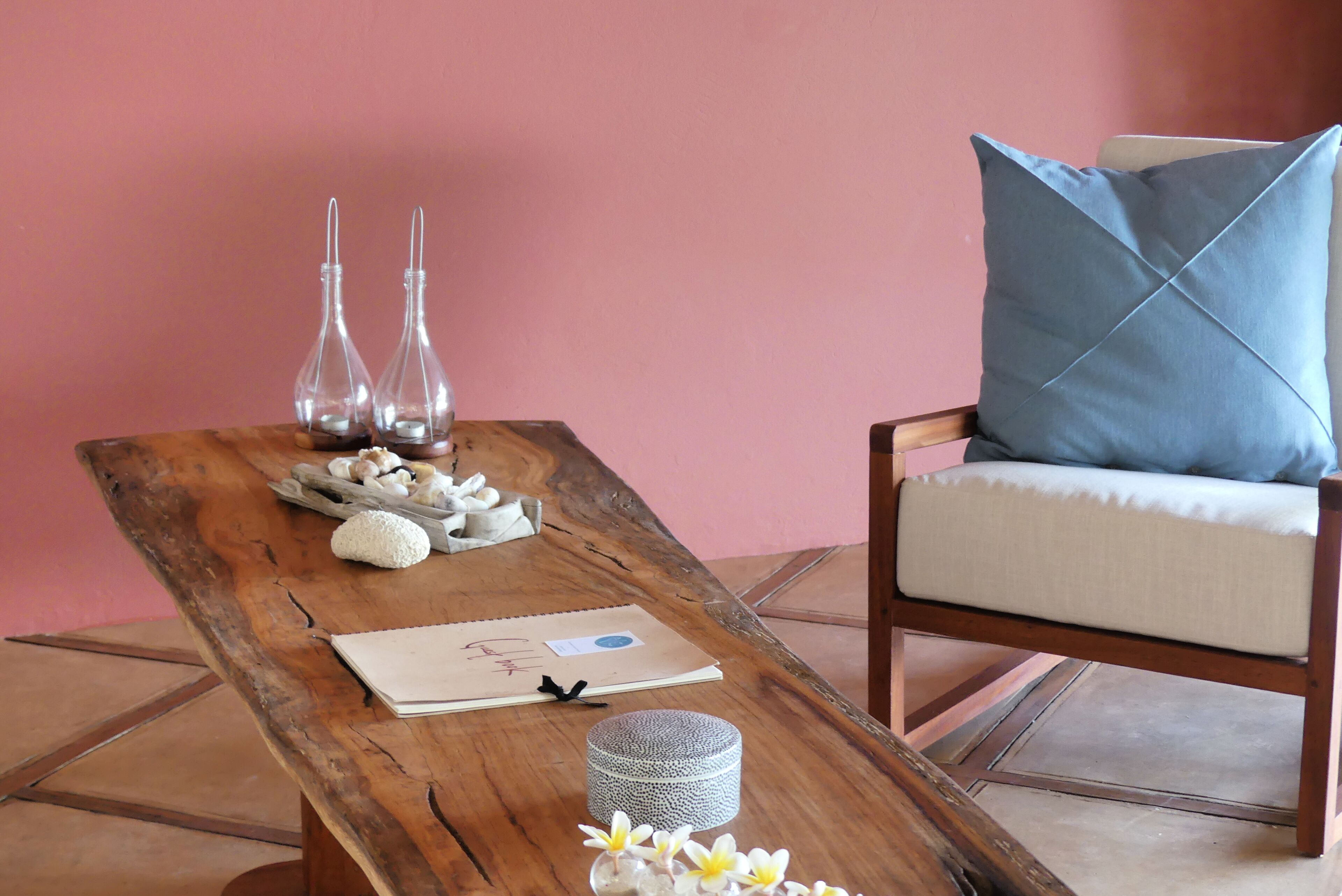 A wooden table with a notebook, two glass bottles, a small basket, and a decorative item.