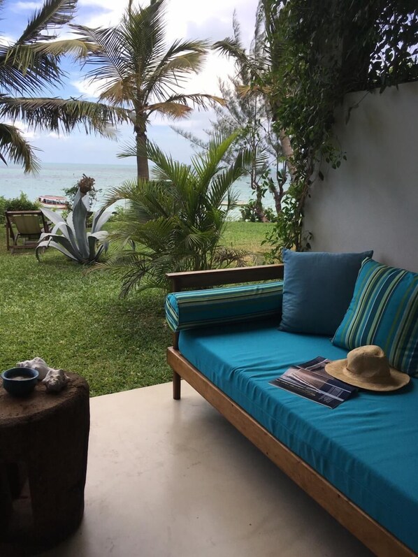 A bedroom with a bed, a small table, and a view of the ocean.