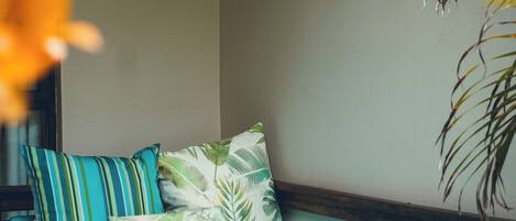 A cozy room with a wooden bench, teal cushions, and a leafy patterned pillow.