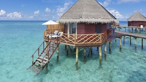Bungalows sobre el agua con techos de paja, pasarelas de madera y agua turquesa cristalina.