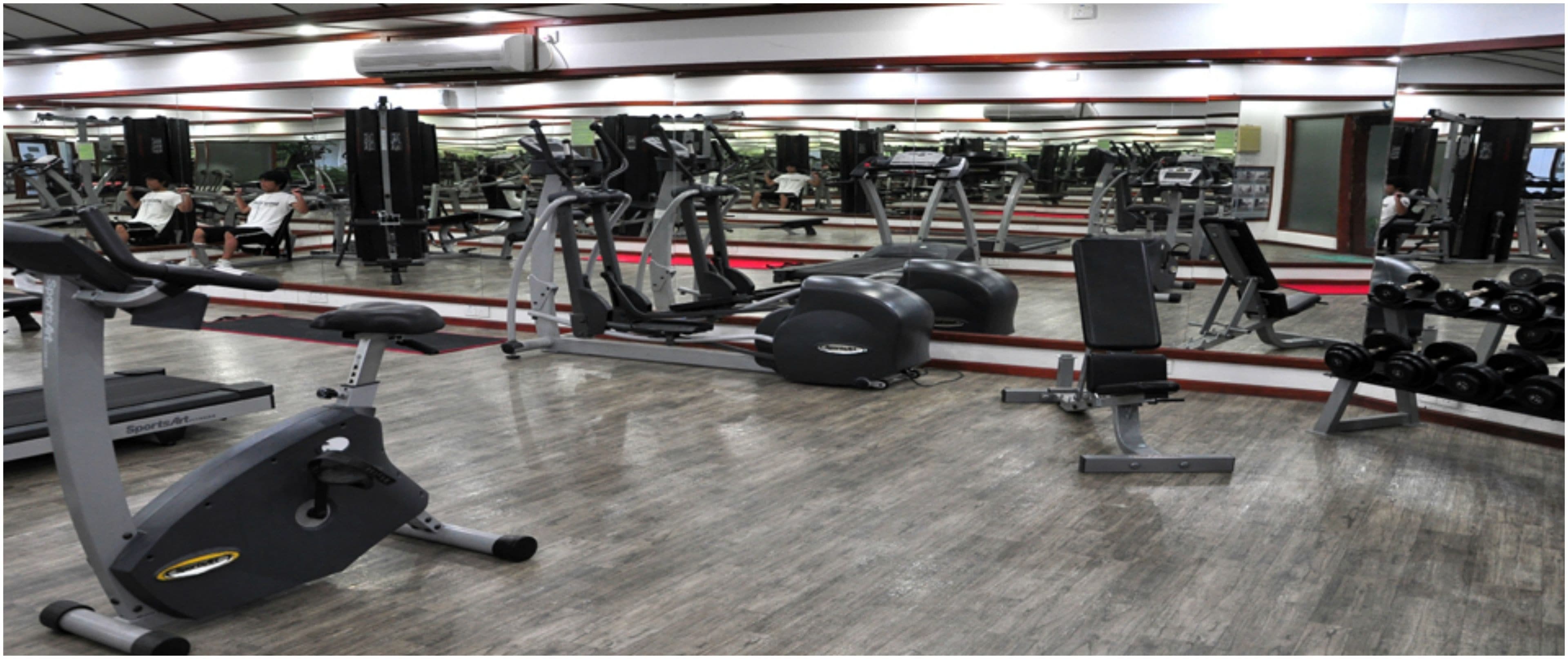 A gym with various exercise equipment, including treadmills, weight machines, and free weights.