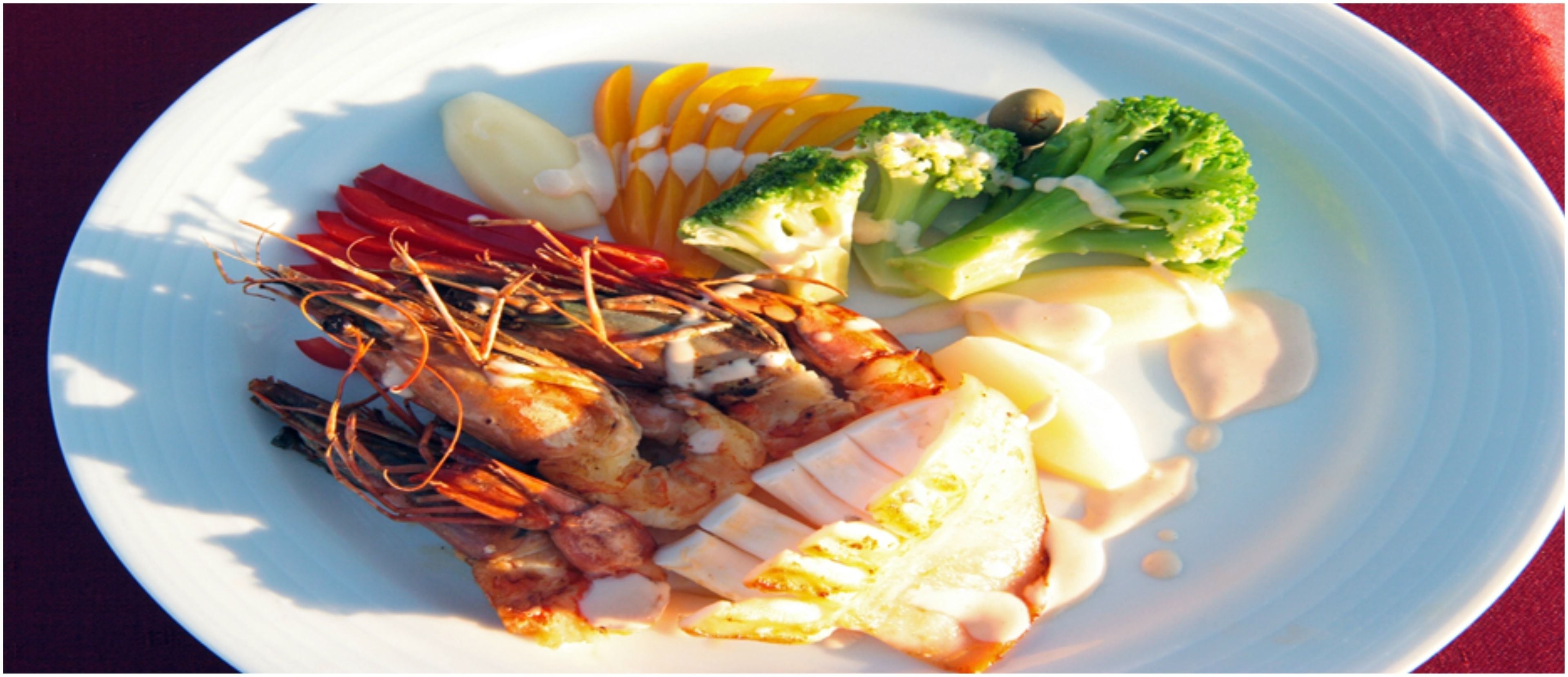 A plate with seafood, vegetables, and a creamy sauce.