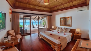 Habitación de hotel con cama, escritorio, silla, ventana con vista a la playa y techo con diseño tejido.