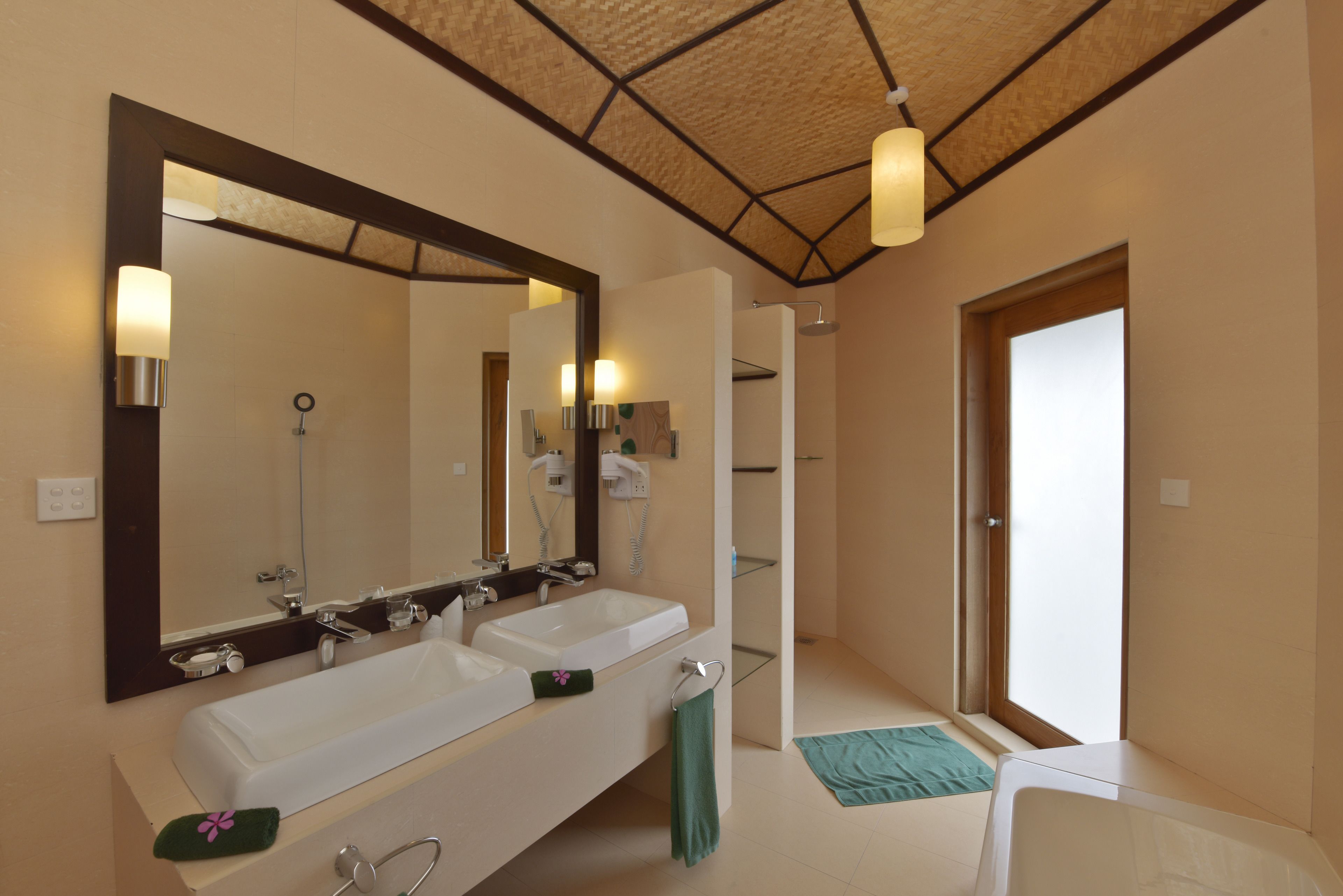 Une salle de bain moderne avec deux lavabos, un grand miroir et un espace douche.