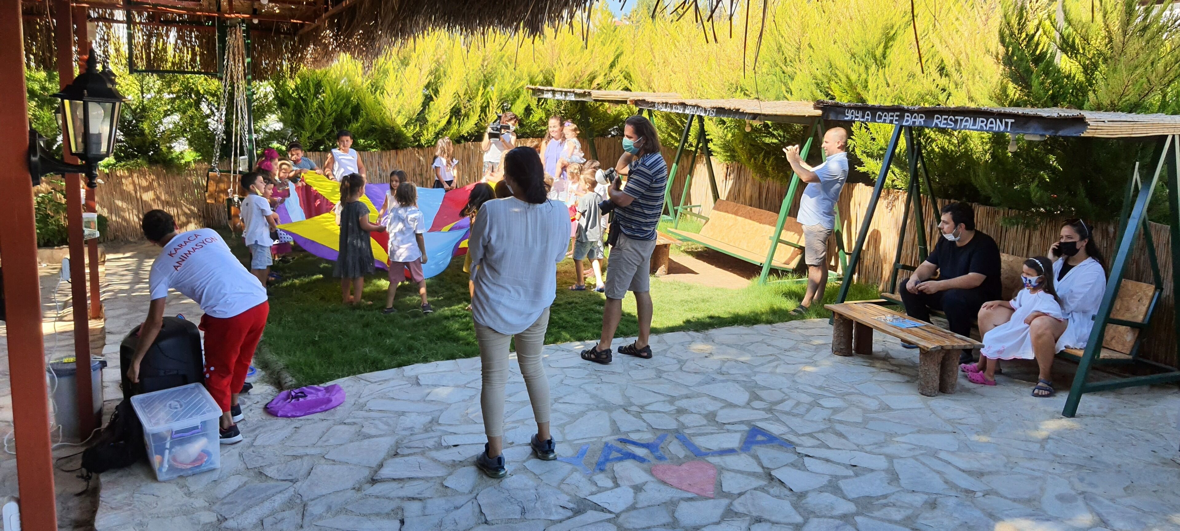 A group of people gathered in an outdoor area with a swing set and a bench.