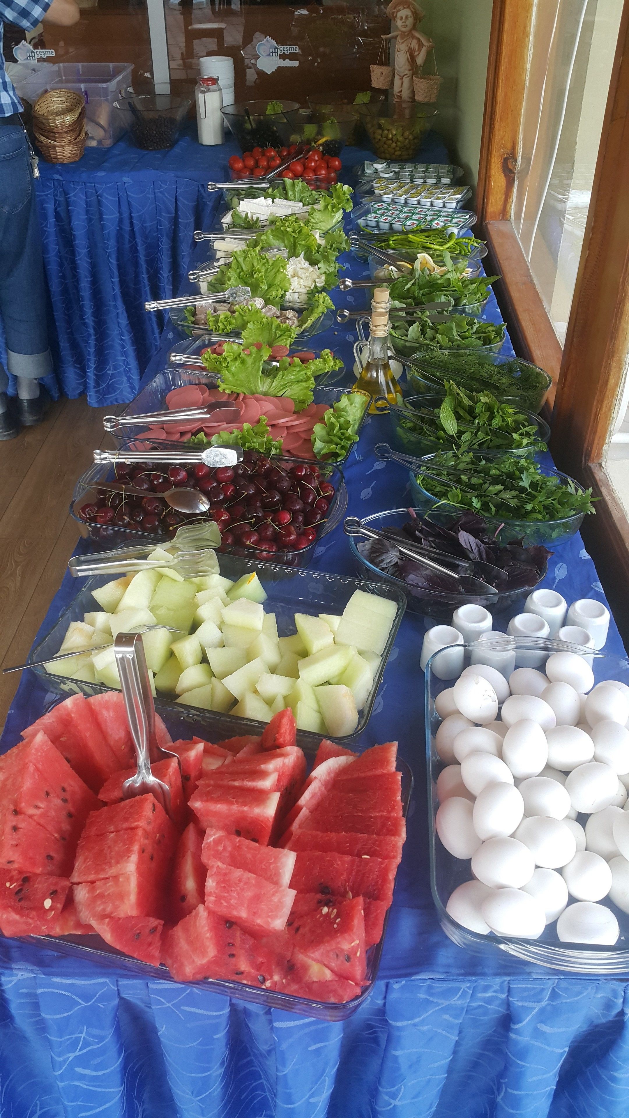 A buffet table with various food items including fruits, vegetables, and eggs.