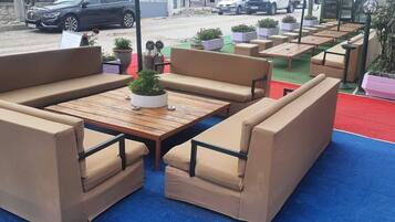Mobiliario exterior con sillas acolchadas y una mesa de madera, rodeado de plantas en macetas.